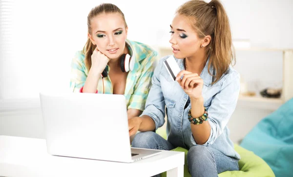 两名年轻妇女坐在笔记本电脑和信用的车在家里 — 图库照片