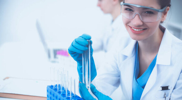 Woman researcher is surrounded by medical vials and flasks, isolated on white background