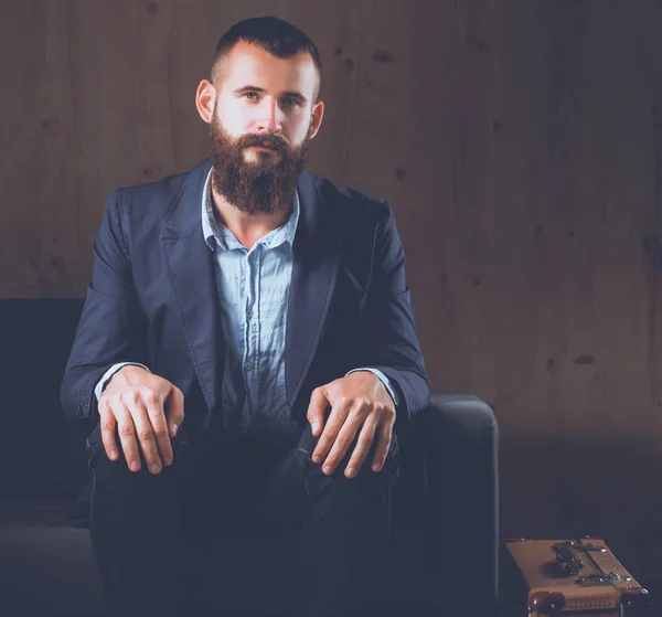 Businessman sitting the sofa in office lobby, isolated on dark background — Stock Photo, Image