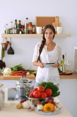Mutfağında yemek için bir tablet bilgisayar kullanan genç kadın. Genç kadın
