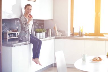 modern mutfakta otururken cep telefonu kullanan kadın.