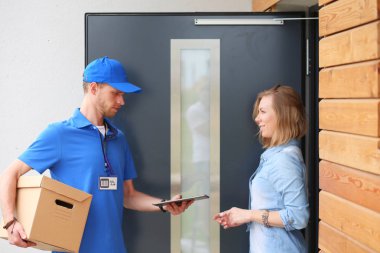 Mavi üniformalı gülümseyen kurye servis konseptine paket kutusu teslim eden teslimatçı. Mavi üniformalı gülümseyen teslimatçı.