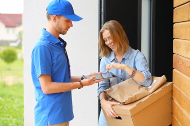 Mavi üniformalı gülümseyen kurye servis konseptine paket kutusu teslim eden teslimatçı. Mavi üniformalı gülümseyen teslimatçı.
