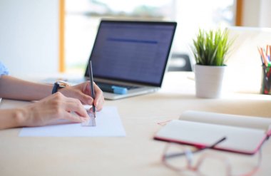 Ofis masasında dizüstü bilgisayarla oturan genç bir kadın. Genç bir kadın. Dizüstü bilgisayar