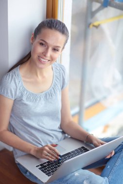 Evde bir dizüstü bilgisayar kullanan genç güzel kadın. Genç güzel kadın.
