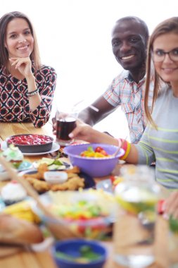 Ahşap masada otururken birlikte yemek yiyen bir grup insanın üst düzey görüntüsü. Masada yemek var. İnsanlar fast food yiyor..