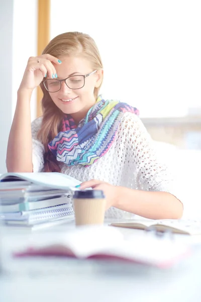 Una joven sentada en un escritorio entre libros. Estudiante — Foto de Stock