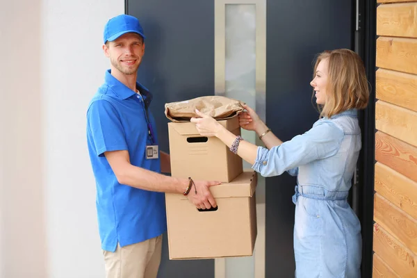 身穿蓝色制服的送货员向收件人-信使服务概念递送包裹箱.穿著蓝色制服的送货员 — 图库照片