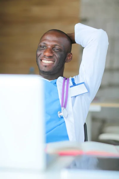 Jeune médecin africain travaillant sur ordinateur portable au bureau. Docteur. Lieu de travail — Photo