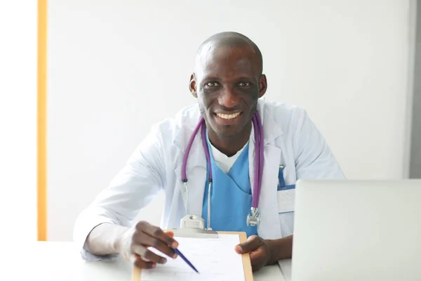 Porträtt av ung manlig läkare bär headset när du använder datorn vid skrivbordet på kliniken. Läkare. — Stockfoto