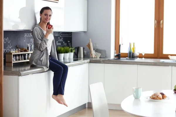 Modern mutfakta otururken cep telefonu kullanan kadın. — Stok fotoğraf