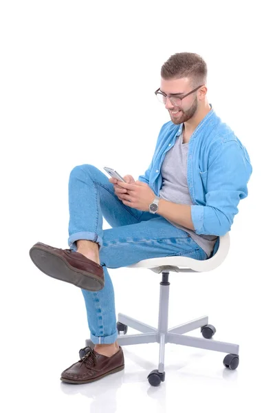 Młody mężczyzna siedzi na krześle i przy użyciu telefonu komórkowego. Startupper. Młody przedsiębiorca. — Zdjęcie stockowe
