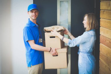 Mavi üniformalı gülümseyen kurye servis konseptine paket kutusu teslim eden teslimatçı. Mavi üniformalı gülümseyen teslimatçı.