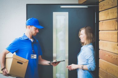 Mavi üniformalı gülümseyen kurye servis konseptine paket kutusu teslim eden teslimatçı. Mavi üniformalı gülümseyen teslimatçı.