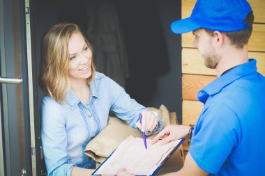 Mavi üniformalı gülümseyen kurye servis konseptine paket kutusu teslim eden teslimatçı. Mavi üniformalı gülümseyen teslimatçı.