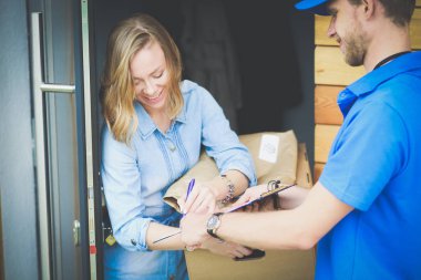 Mavi üniformalı gülümseyen kurye servis konseptine paket kutusu teslim eden teslimatçı. Mavi üniformalı gülümseyen teslimatçı.