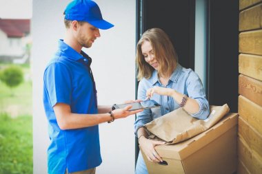 Mavi üniformalı gülümseyen kurye servis konseptine paket kutusu teslim eden teslimatçı. Mavi üniformalı gülümseyen teslimatçı.