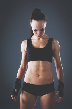 Gri arka plan üzerinde duran kas genç kadın. Kas genç kadın