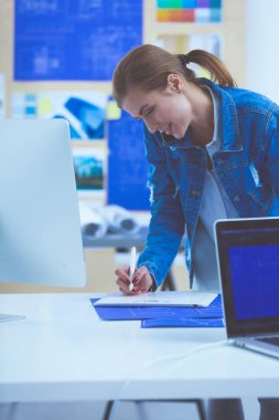 Masanın yanında duran iki genç kadın enstrüman, plan ve dizüstü bilgisayarla.