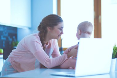 Annesi bebeğini evde parlak mutfakta ile.