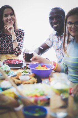 Ahşap masada otururken birlikte yemek yiyen bir grup insanın üst düzey görüntüsü. Masada yemek var. İnsanlar fast food yiyor..