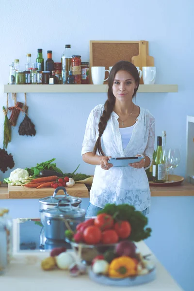 Eine junge Frau kocht mit einem Tablet-Computer in ihrer Küche. junge Frau — Stockfoto