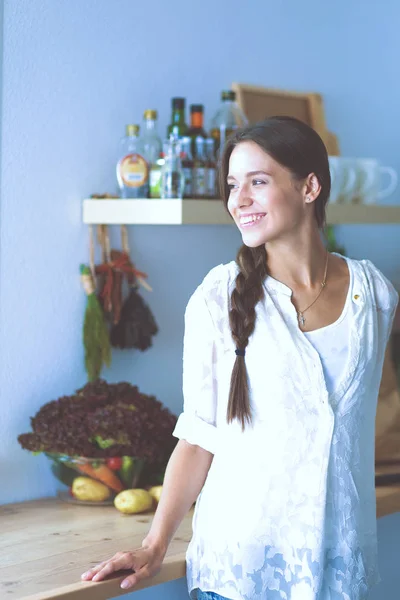 Ung kvinna står nära skrivbordet i köket. Ung kvinna . — Stockfoto