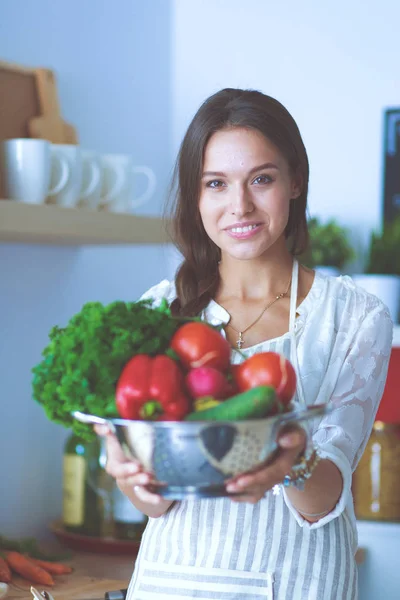 Una giovane donna sorridente che tiene le verdure in cucina. Sorridente giovane donna — Foto Stock