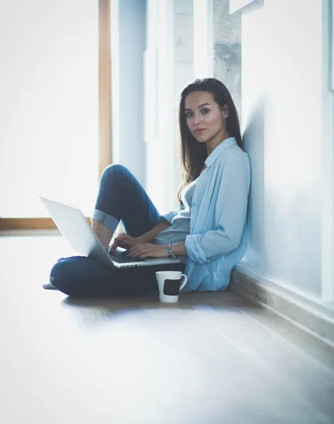 年轻漂亮的女人在家里坐在用笔记本电脑在地板上。年轻漂亮的女人. — 图库照片