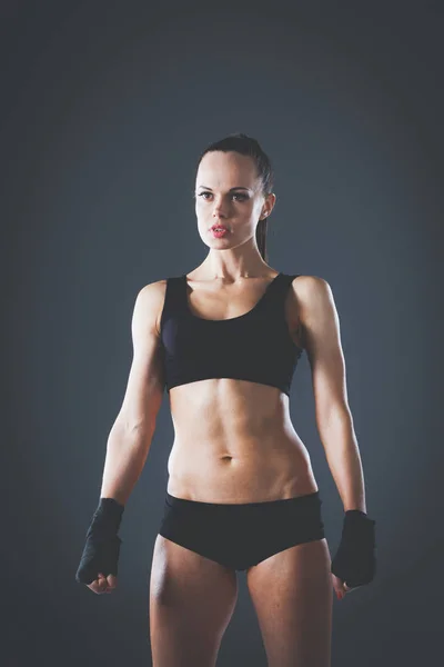 Muskulöse junge Frau, die auf grauem Hintergrund steht. muskulöse junge Frau — Stockfoto