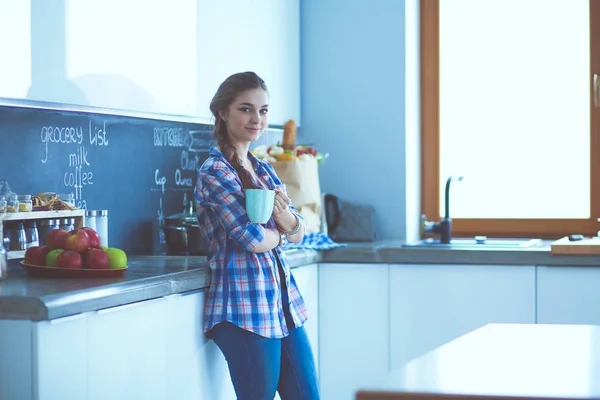Lycklig kvinna dricka te i köket hemma. — Stockfoto