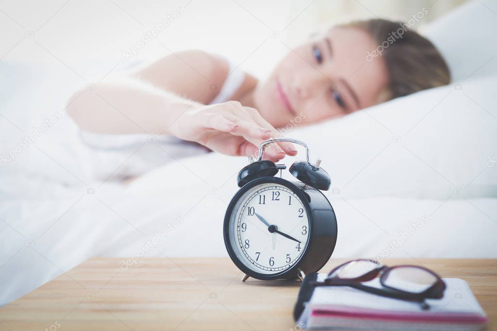 Young sleeping woman and alarm clock in bedroom at home. Young sleeping woman.