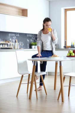 Mutfakta portakal suyu ve tableti olan genç bir kadın..