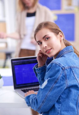 İki genç kadın masada enstrümanlar, planlar ve dizüstü bilgisayarlarla oturuyor..