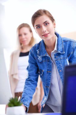 Masanın yanında duran iki genç kadın enstrüman, plan ve dizüstü bilgisayarla.