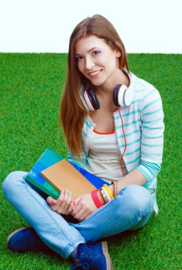 Yeşil çimlerde oturan dizüstü bilgisayarı olan genç bir kadın. Portreit genç bayan