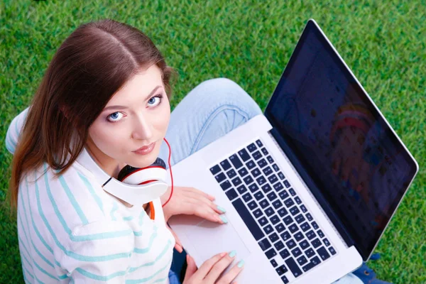 Jovem com laptop sentado na grama verde. Portreit jovem mulher — Fotografia de Stock