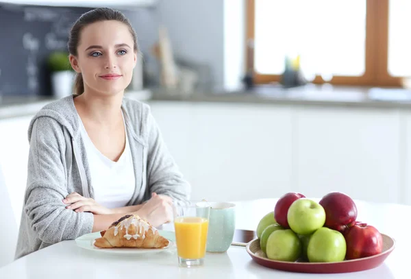 Ung kvinna med apelsinjuice och tablett i köket. — Stockfoto