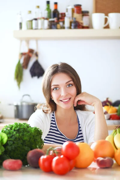 Mujer joven de pie cerca de escritorio en la cocina. Mujer joven . — Foto de Stock