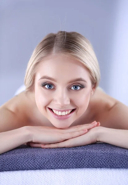 Mujer joven acostada en una mesa de masaje, relajada. Una mujer. Salón de spa —  Fotos de Stock