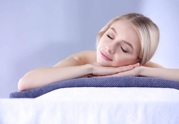 Mujer joven acostada en una mesa de masaje, relajándose con los ojos cerrados. Una mujer. Salón de spa — Foto de Stock