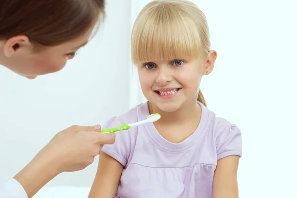 Tandläkare och liten flicka på tandläkarmottagningen . — Stockfoto