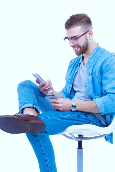 Jeune homme assis sur une chaise et utilisant un téléphone portable. Démarreur. Jeune entrepreneur . — Photo