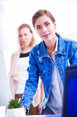 Masanın yanında duran iki genç kadın enstrüman, plan ve dizüstü bilgisayarla.