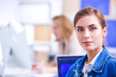 İki genç kadın masada enstrümanlar, planlar ve dizüstü bilgisayarlarla oturuyor..