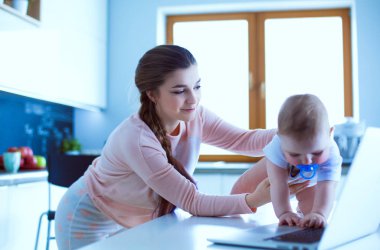 Annesi bebeğini evde parlak mutfakta ile.