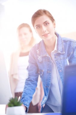 Masanın yanında duran iki genç kadın enstrüman, plan ve dizüstü bilgisayarla.