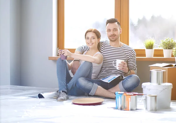 Retrato feliz sorrindo jovem casal pintura parede interior da nova casa. Casal jovem — Fotografia de Stock