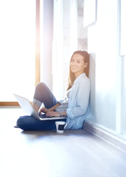 Jeune belle femme à la maison assise sur le sol avec ordinateur portable. Jeune belle femme . — Photo