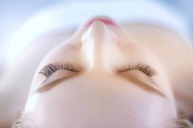 Masaj masasında uzanmış gözleri kapalı rahatlayan genç bir kadın. - Kadın. Spa salonu